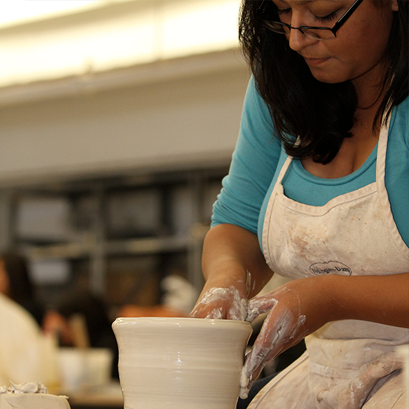 Student sitting cross legged in a studio setting.
