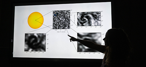 An astronomy student explains images displayed on a projector in a dark room