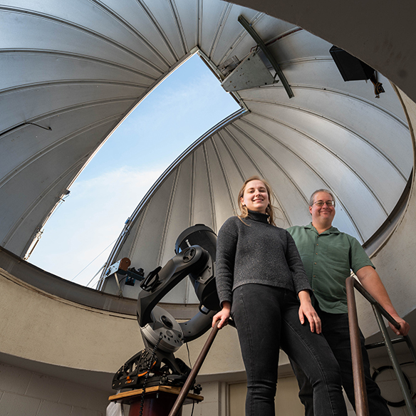 a man and woman stand inside a large telescope