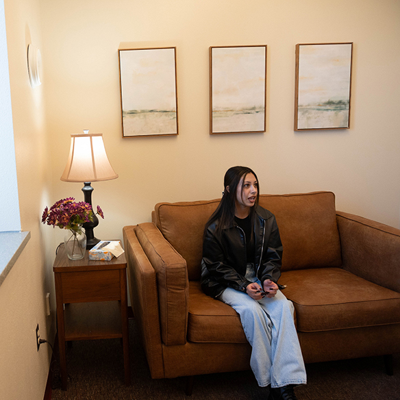a counseling patient sits on a couch speaking to her therapist. 