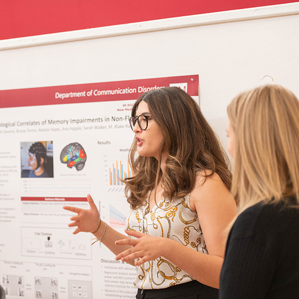 A female student speaks to others about her research regarding communication disorders. 