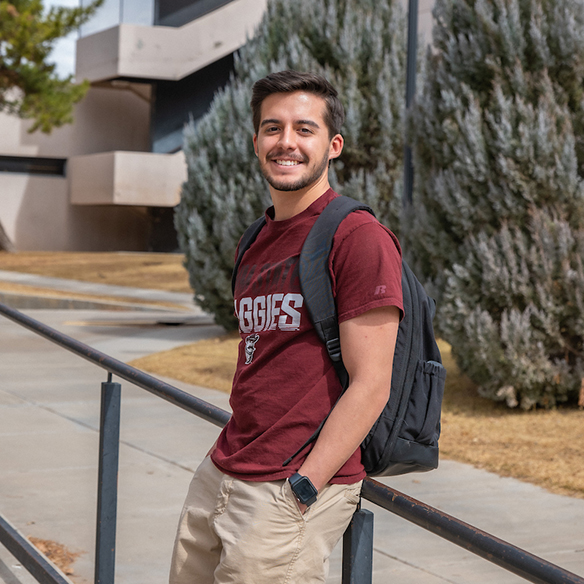 a male student leaning on a railing on the NMSU campus