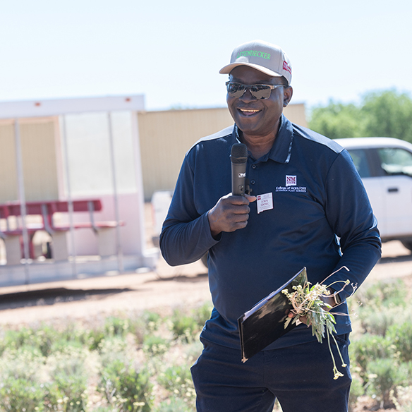 a man talks to a group about plant sciences in a field