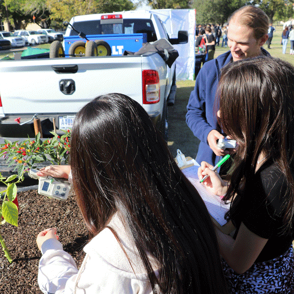 Student teaching kids about plants in an outdoor setting.
