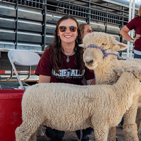 Student smiling behind two lambs.