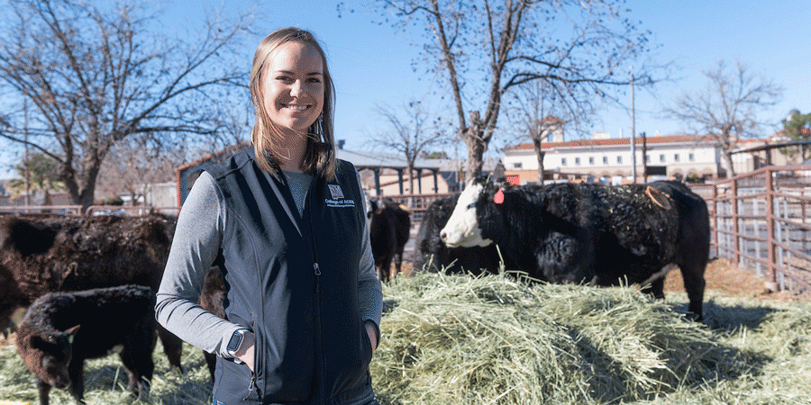 Student at farm with cattle in the background.
