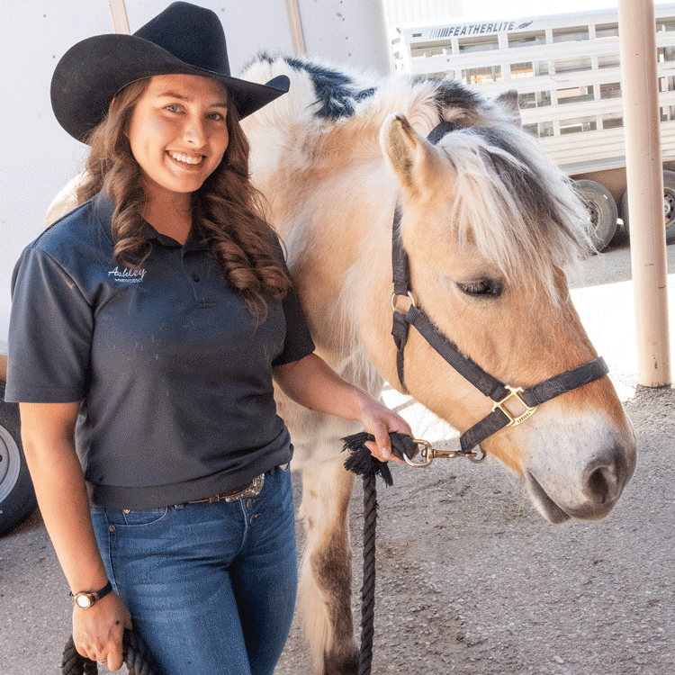 Student at farm with cattle in the background.
