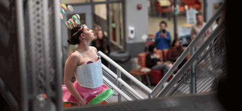 Student with bright dress and head accessory at fashion show.