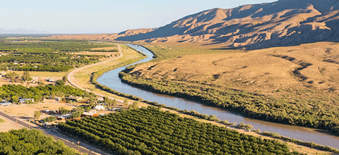 View of stream flowing through a lanscape with mountains in the distance.