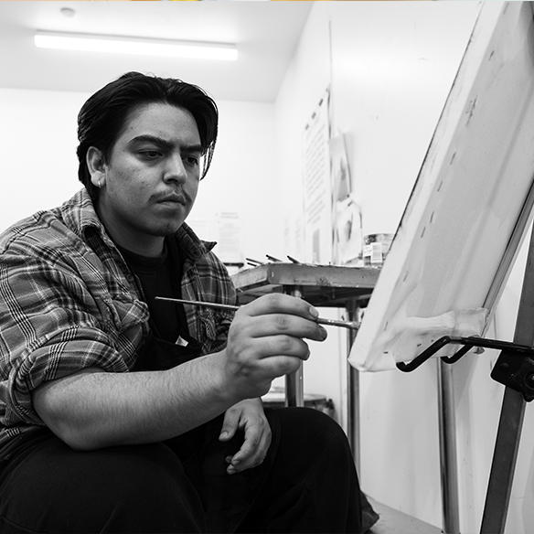 Man holding a paintbrush in front of a canvas