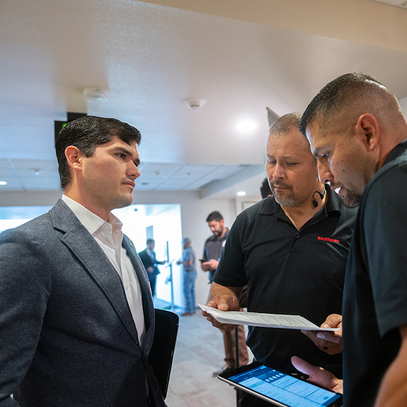 A male student in a suit speaking with recruiters