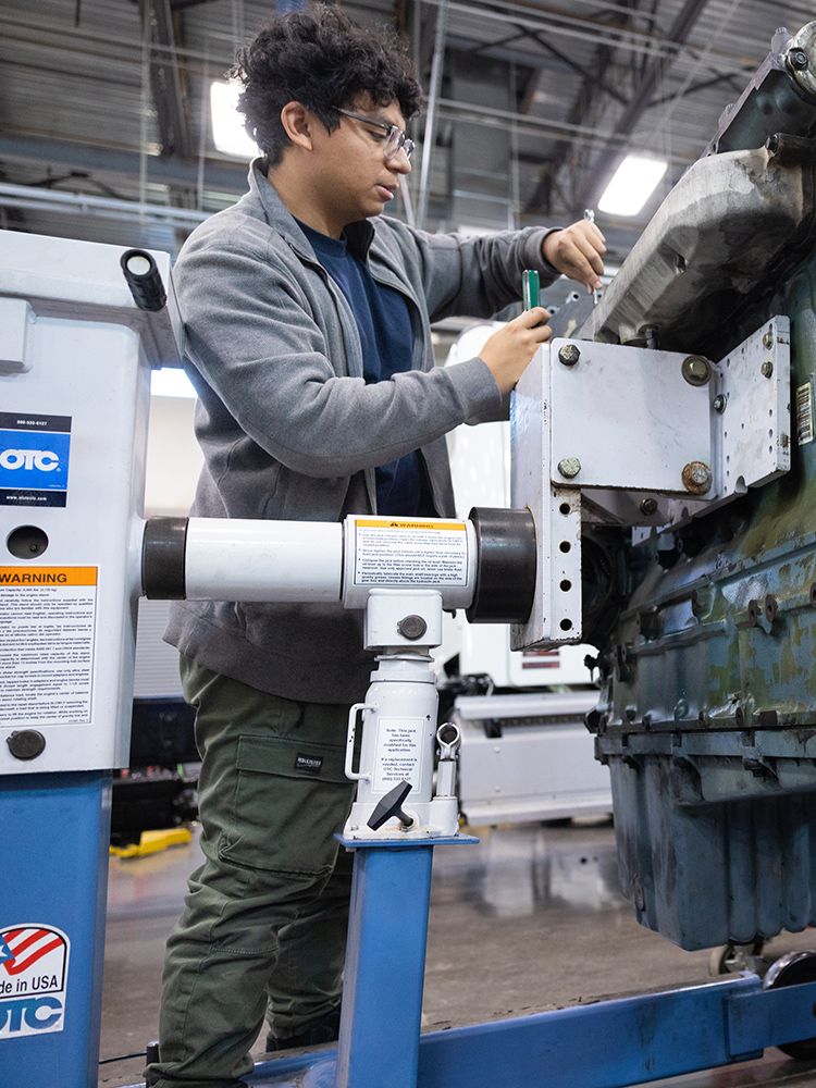 student adjusting fasteners on an engine