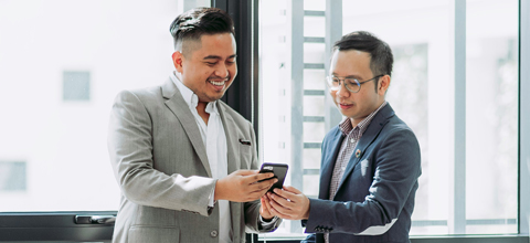 two businessmen looking at a cell phone