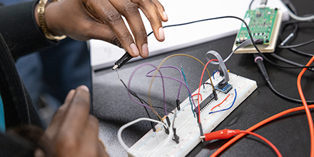 Black female student working on computer hardware during a computer engineering class on a college campus.