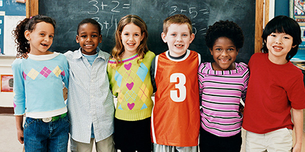 Elementary School Children posing for photograph in front of chalkboard