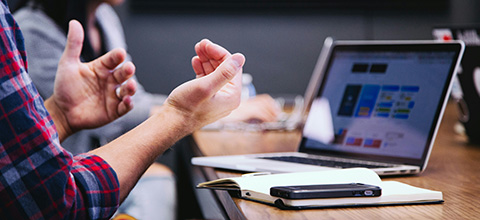 an employee speaking in a meeting while looking at a laptop
